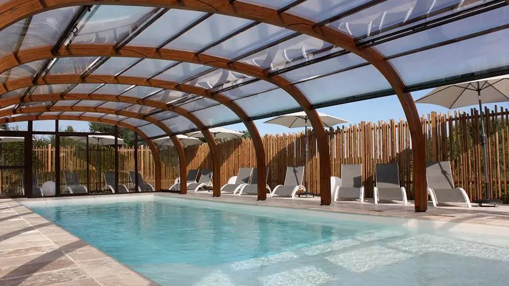 Piscine couverte chauffée du domaine Volcans Vacances — structure bois arrondie